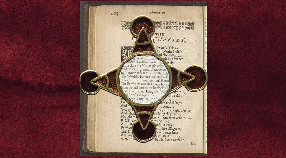 A page from an old book with a glass pendant overlaid over it, highlighting specific letters of the text